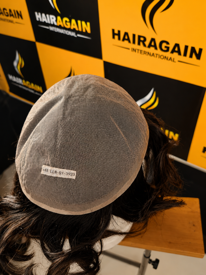Gray cap on a mannequin head with Hairagain International branding in the background