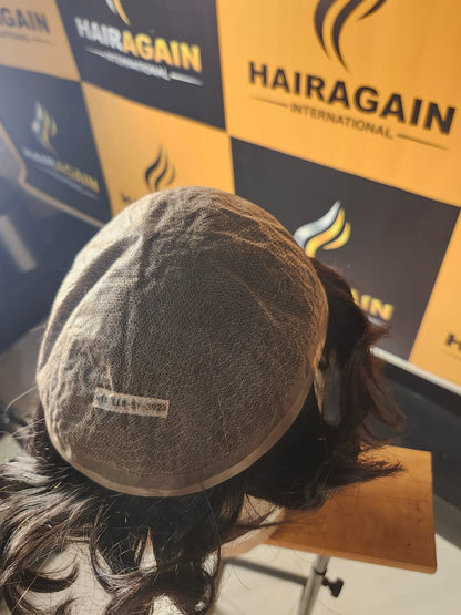 Person wearing a hairpiece with 'HairAgain' branding in the background